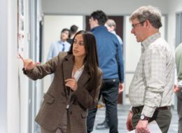 Student researcher points at poster